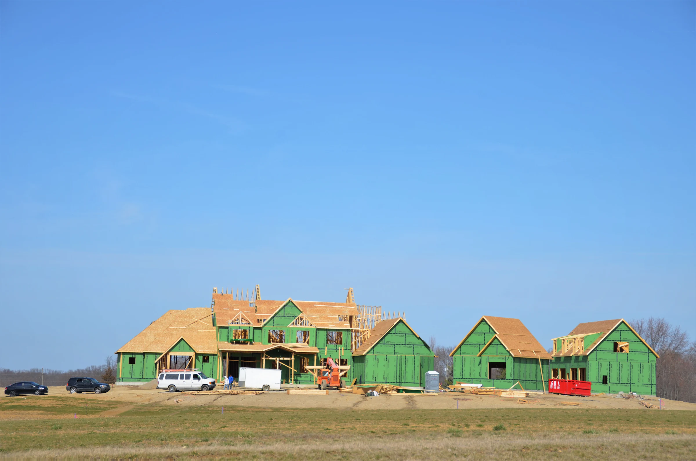 Mehrere Häuser im Rohbau auf einem freien Baufeld unter blauem Himmel
