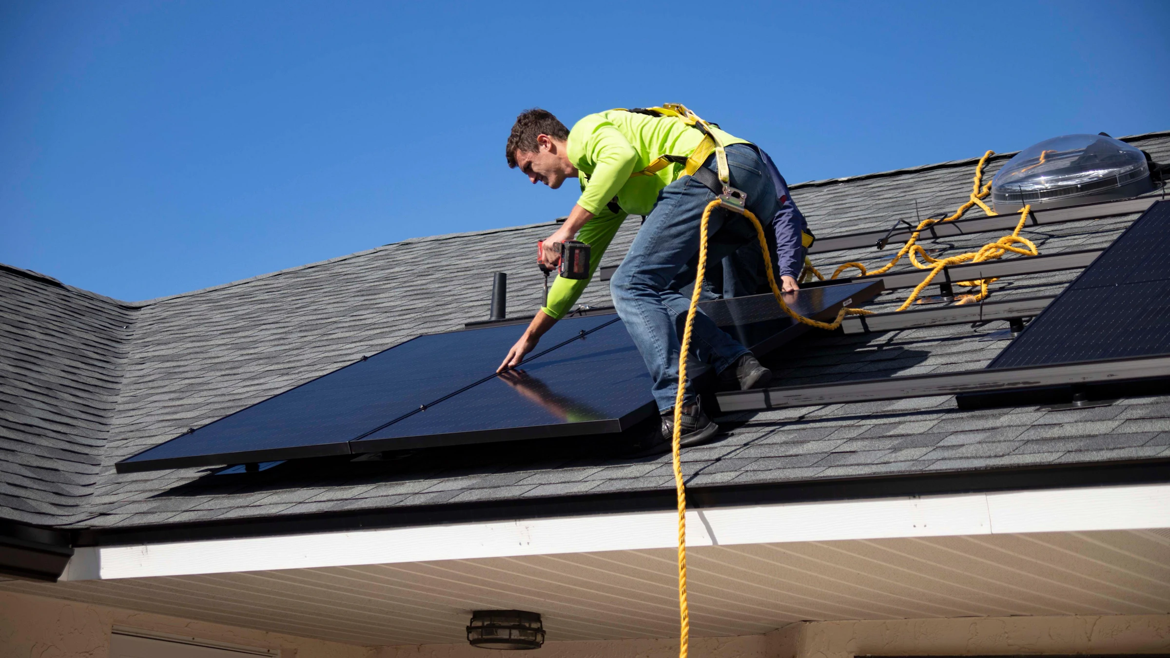 Monteur in Warnkleidung montiert Solarmodule auf einem Hausdach