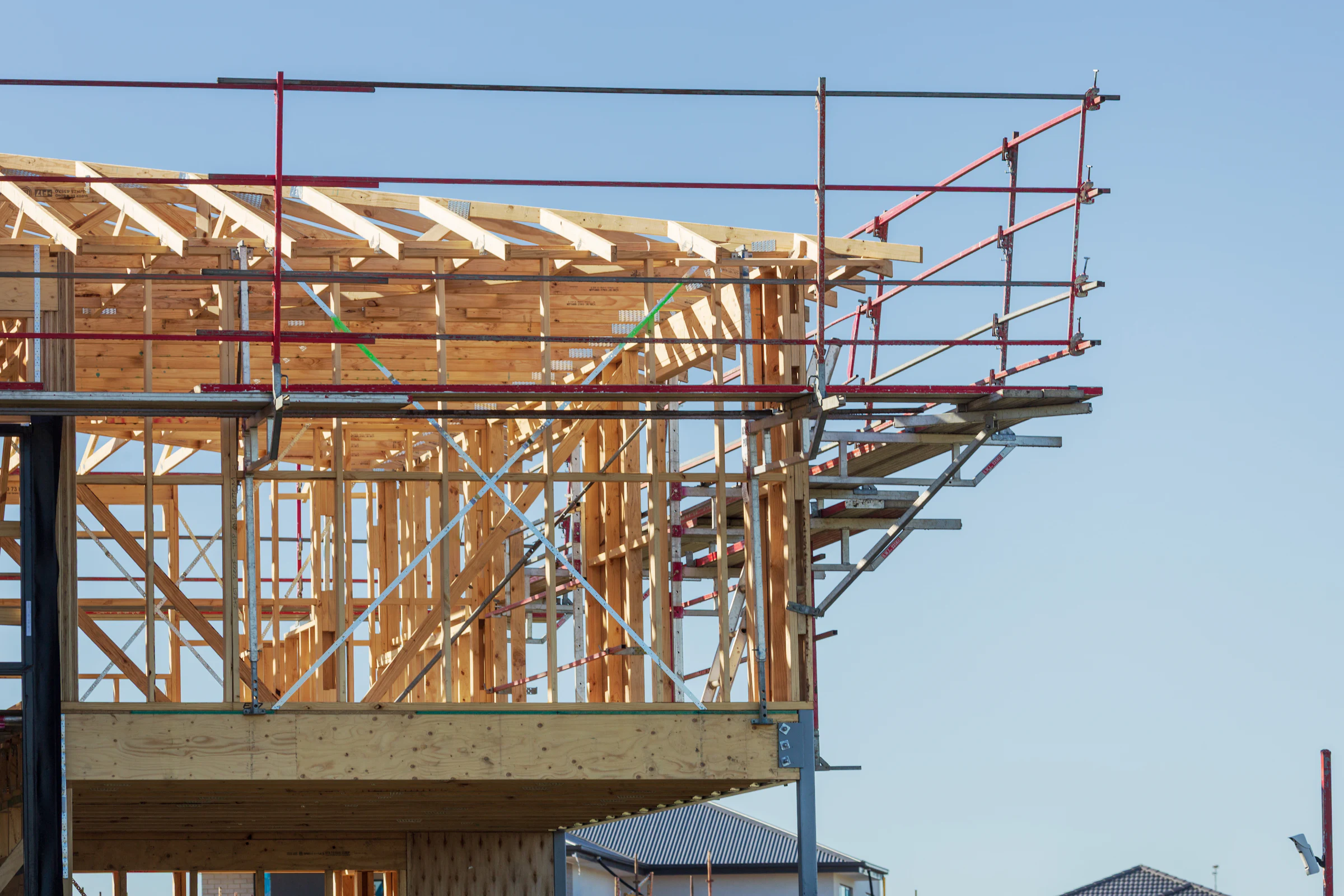 Holzrahmen eines Hauses im Bau mit Gerüst vor blauem Himmel