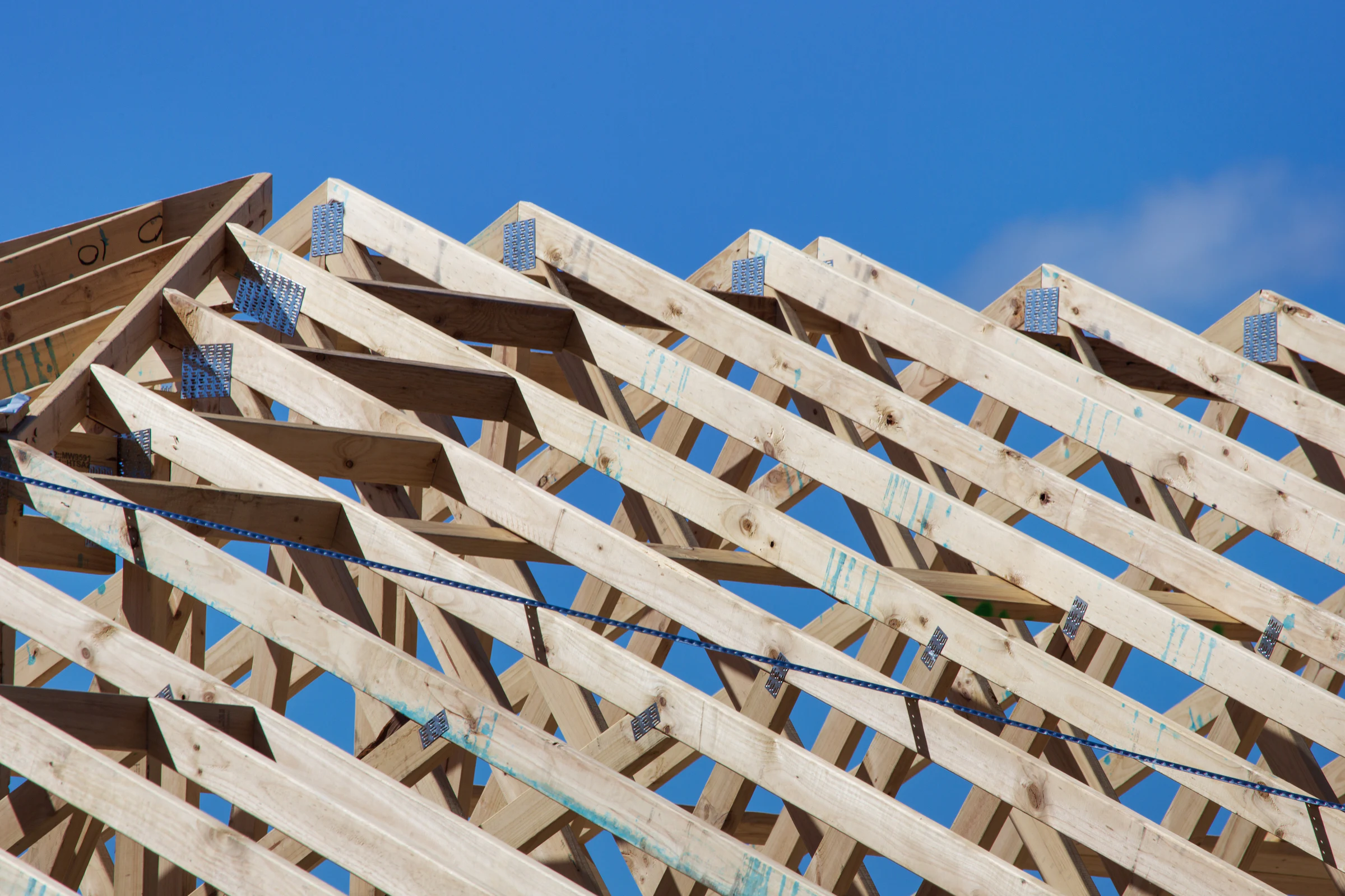 Frisch gezimmerter Dachstuhl aus hellem Holz vor blauem Himmel
